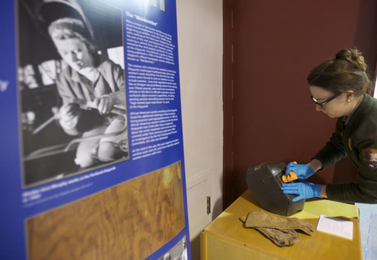 Meagan Huff, Fort Vancouver National Historic Site museum technician, puts the finishing touches on a display that includes welding gear used by Betty Jane Budd at Vancouver's Kaiser Shipyard.