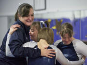 Coach Sheri Bousquet embraces team members, from left, Geneva &quot;Gigi&quot; Gernhart, Hadley Park and Carissa Brown following the balance beam portion of Sunday's meet at Naydenov Gymnastics.