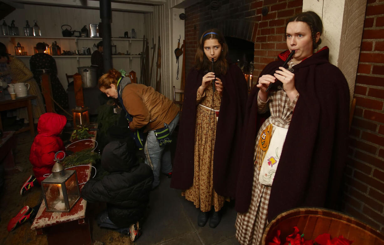 Megan Bruns, 16, center, and Megan Wilcox, 18, play Christmas carols on penny whistles at Fort Vancouver. Re-enactors could be found in every corner of the stockade as stories were spun and songs sung at the fort&#039;s annual holiday event.