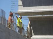 Workers stand atop the skeleton of what will soon form the Northeast 139th Street overpass and guide 175,000-pound girders into place. The work is part of the Salmon Creek Interchange Project, which required both north and south lanes of Interstate 5 be closed Saturday.