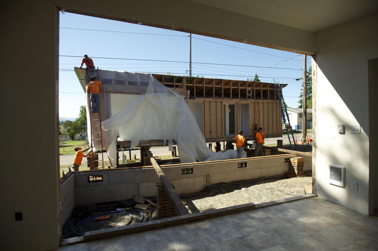 Workmen prepare to roll the front half of a house onto its foundation and match it up with the back half of the modular, already in place, in September 2013. The house was built by Mountain View and Evergreen high school students in partnership with Evergreen Habitat for Humanity. That organization is one of six local nonprofit agencies that will share a $1.1 million Department of Labor &quot;YouthBuild&quot; grant.