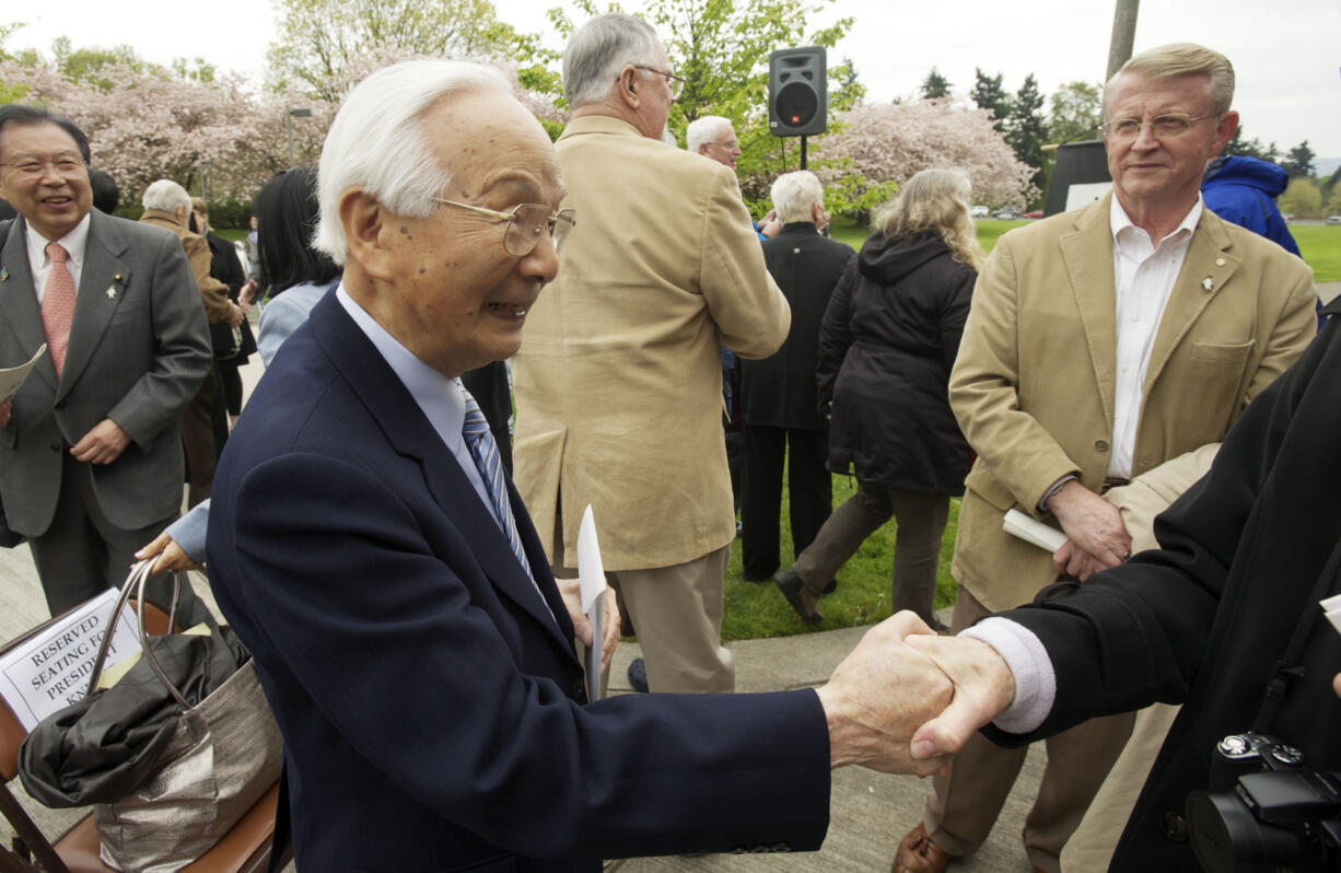 Atsushi Kageyama shakes hands with a guest as his old friend, former mayor Bruce Hagensen, right, watches.