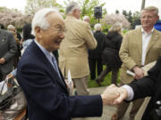 Atsushi Kageyama shakes hands with a guest as his old friend, former mayor Bruce Hagensen, right, watches.