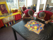 Tibetan monks Lobsang Yeshi, left, and Ngaweng Choegyal use a tiny metal funnel called a &quot;chakpur&quot; Tuesday to create a sand mandala, or sand painting, at Clark College's Cannell Library in Vancouver. A closing ceremony, when the artwork will be destroyed, is set for 3 p.m.