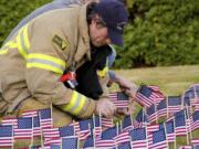 Hazel Dell: Firefighter Casey Taylor places flags in the ground to honor fallen firefighters at the Fire District 6 remembrance ceremony on Sept.