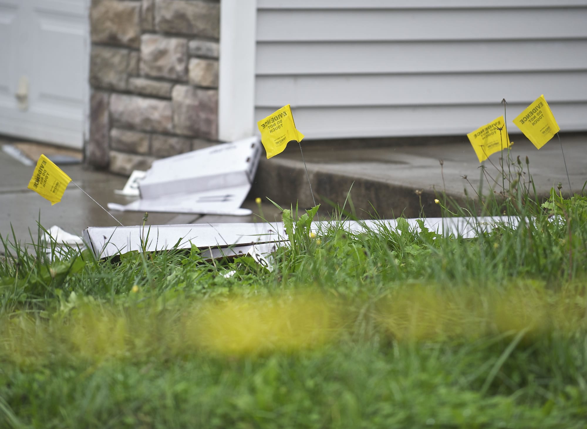 Flags mark evidence in the front lawn of a Sunnyside house where Clark County Sheriff's Office detectives say two people were stabbed, one fatally, early Saturday morning.