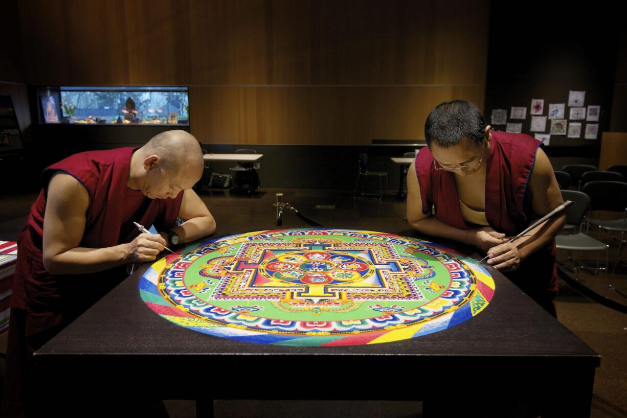 Nawang Jamyang, left, and Nawang Tenphel, right, put the finishing touches on a sand mandala Friday afternoon at the Vancouver Community Library.