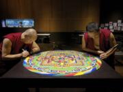 Nawang Jamyang, left, and Nawang Tenphel, right, put the finishing touches on a sand mandala Friday afternoon at the Vancouver Community Library.