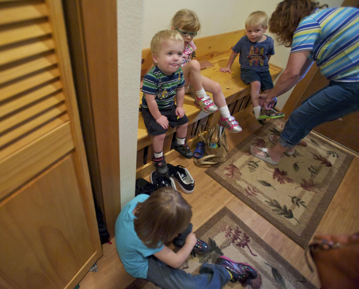 Julianne Johnson helps her children, from left, Baily, 5, Elijah, 23-months, Bree, 4,  and Tito, 3, get their shoes on before heading to downtown La Center.