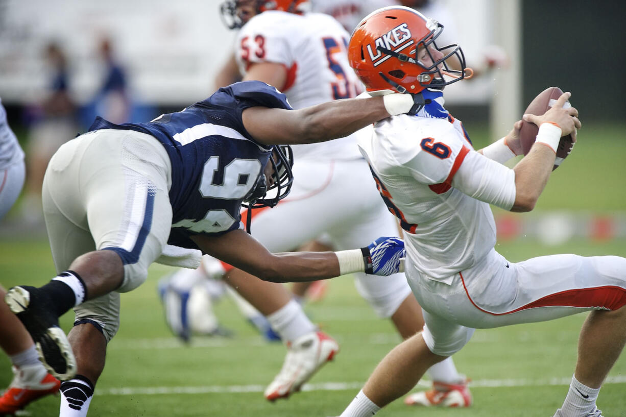 Rayshawn Wess, 94, of Skyview High School sacks quarterback Rhys Gervais, 6, of Lakes High School during the second half in a game at Kiggins Bowl on Friday.