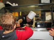 Battle Ground Police Chief Bob Richardson serves hot dogs on healthful wheat buns to full-day kindergarteners in Sue Hillis class at Maple Grove K-8 School on Oct.