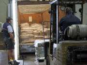 Postal Service truck driver Jim Dann, left, watches forklift operator Ricardo Ibarra load 23 pallets of Clark County ballots onto his truck at Signature Graphics in Northeast Portland on Monday. Dann took the ballots to the post office.