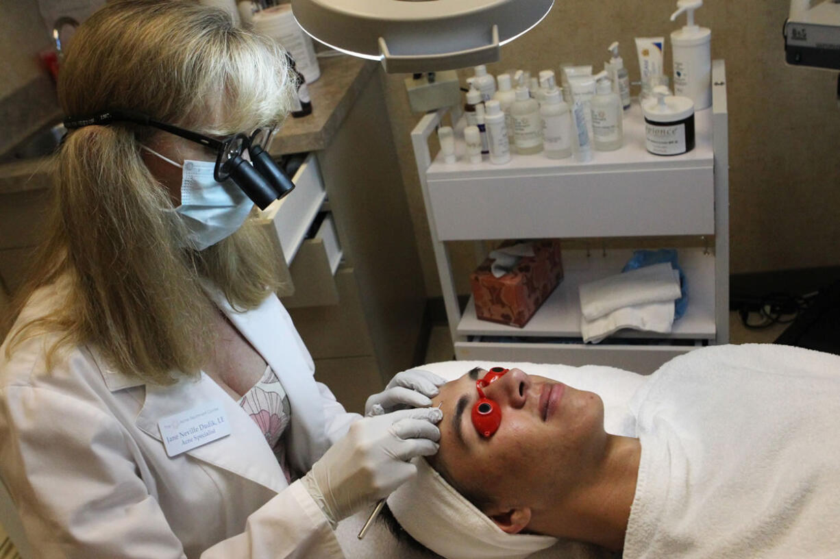 Jane Dudik, owner of Acne Treatment Center in Vancouver, works on client Brennan Dyehouse, 16.