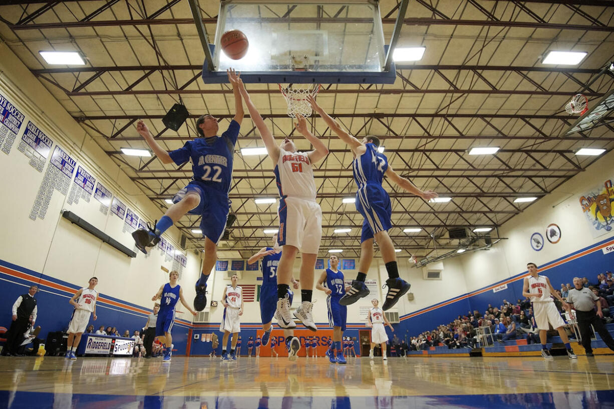 AJ Olson, 51, of Ridgefield for a rebound against Jamison Benitez, 22, and Jeremiah Arn of La Center in the season-opening game for both teams.