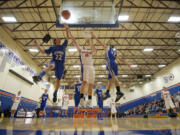 AJ Olson, 51, of Ridgefield for a rebound against Jamison Benitez, 22, and Jeremiah Arn of La Center in the season-opening game for both teams.