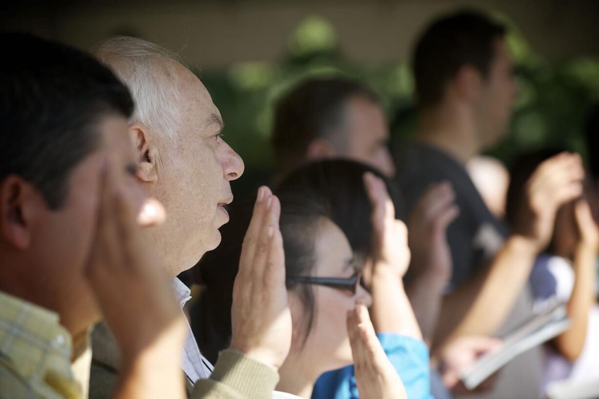 Citizenship candidates raise their right hands and recite the oath of allegiance to the United States of America during Friday's naturalization ceremony at the Fort Vancouver National Historic Site.