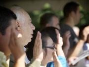 Citizenship candidates raise their right hands and recite the oath of allegiance to the United States of America during Friday's naturalization ceremony at the Fort Vancouver National Historic Site.