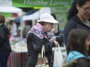 SNAP client Marie Mueller, 62, of Camas carries a bag of fruit and fresh bread she bought Wednesday at the Camas Farmer's Market.