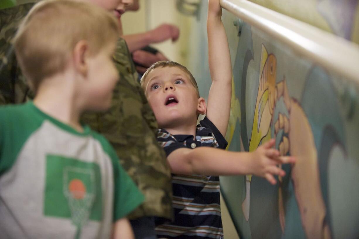 Logan Volk, 4, gets a hands-on look July 20 as Legacy Salmon Creek Hospital unveils a new mural, created by local artist Rebecca Anstine, in a stairwell used for pediatric rehab and physical therapy.