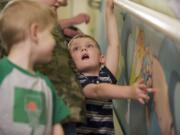 Logan Volk, 4, gets a hands-on look July 20 as Legacy Salmon Creek Hospital unveils a new mural, created by local artist Rebecca Anstine, in a stairwell used for pediatric rehab and physical therapy.