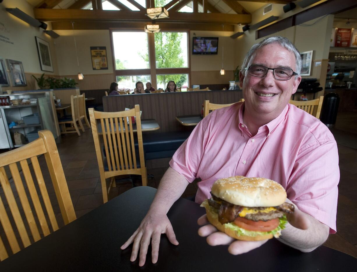 Burgerville CEO and President Jeff Harvey holds a Half Pound Colossal Cheeseburger with bacon at the company's Salmon Creek restaurant.