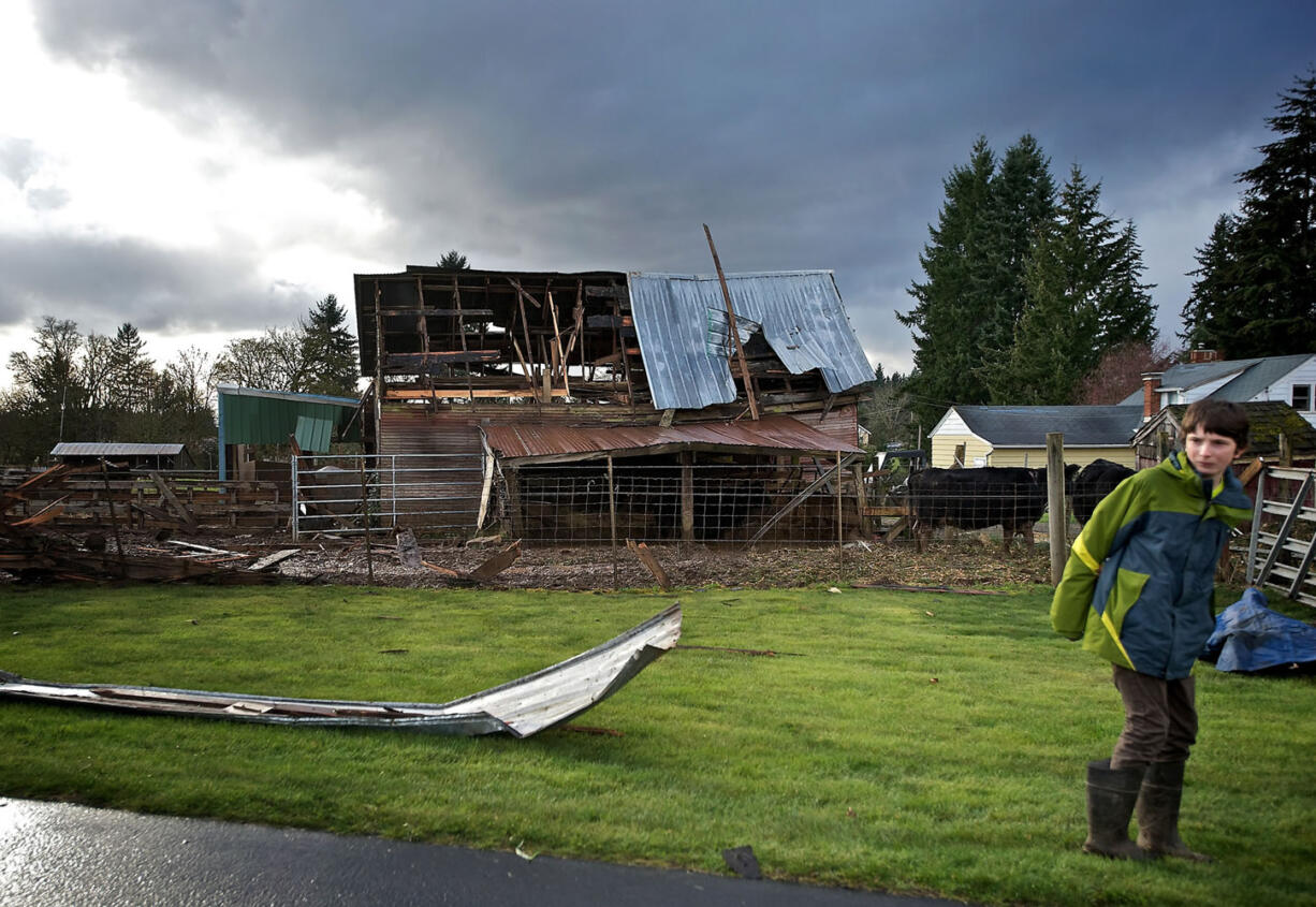 Eathan Ginter, 11, stands next to his grandfather', barn after a tornado-like wind tore the roof off in Hockinson on Thursday.