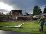 Eathan Ginter, 11, stands next to his grandfather', barn after a tornado-like wind tore the roof off in Hockinson on Thursday.