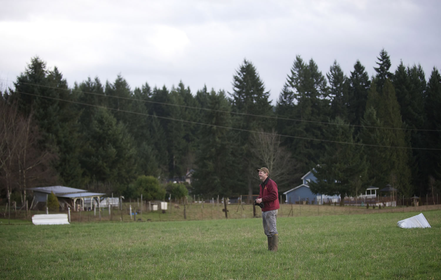 Mike Ginter helps collect pieces of his father', barn after a tornado-like wind tore the roof off, sending peices approximately 600 feet away and in to a field in Hockinson on Thursday.