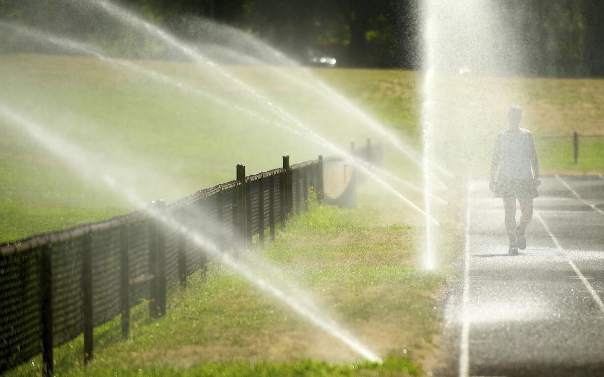 Cindy Filer of Portland stays cool during a walk on a track at Hudson's Bay High School on Wednesday in Vancouver.