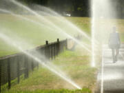 Cindy Filer of Portland stays cool during a walk on a track at Hudson's Bay High School on Wednesday in Vancouver.