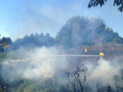 Firefighters work Monday evening to extinguish a 2-acre fire in Ridgefield.