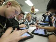 Tyler Aland, 14, from left, Jesse Schneider, 14, Teryn Siebers, 13, and Daniel Perez, 13, use iPads to solve math equations at Discovery Middle School. In the background observing, center, is Holly Palmersheim, technology professional development at Cedar Rapids Community School District in Iowa.