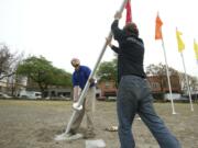 Chris Gonzalez, left, and Jon Penfold of Elmer's Flag and Banner set 10 22-foot flag poles at Block 10 on Friday.