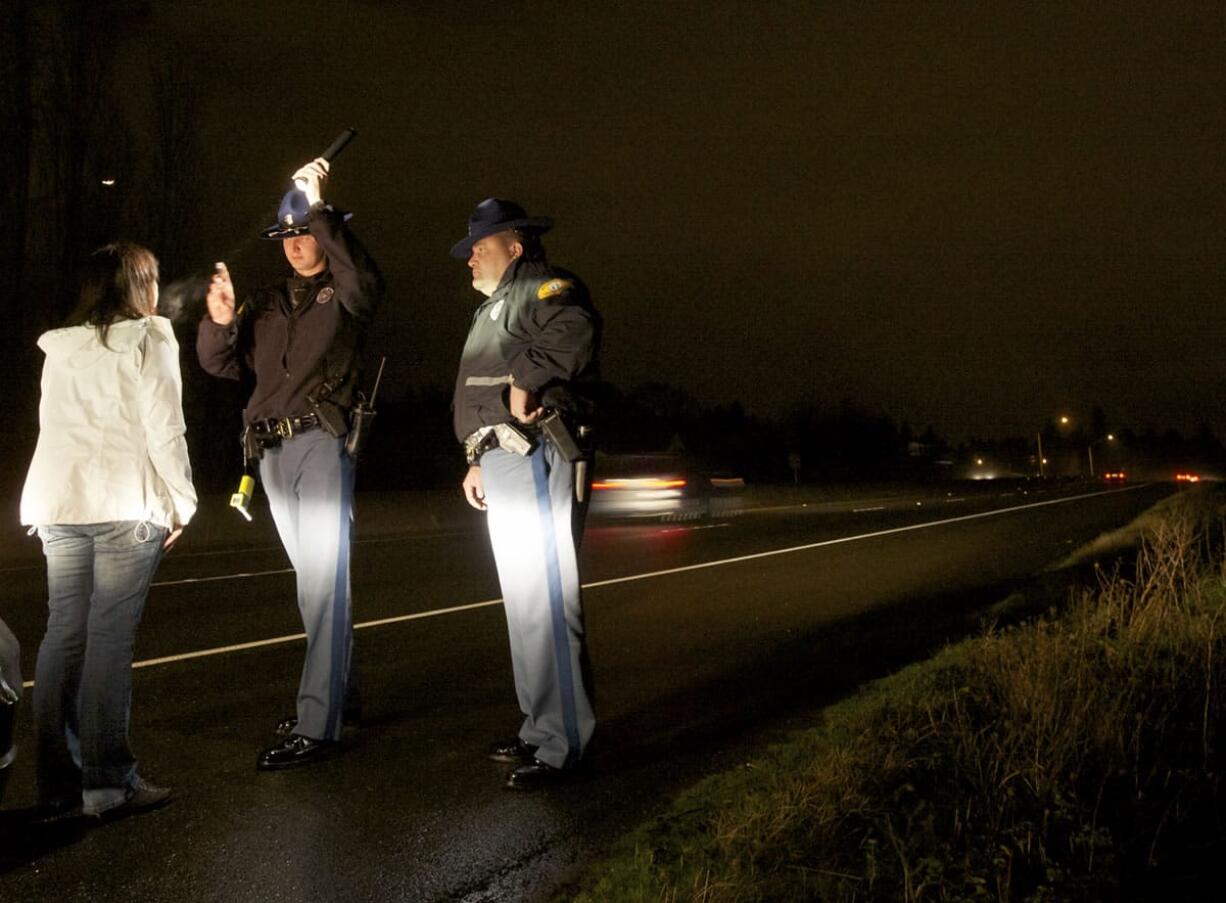 Washington State Patrol Cadet Aleksandr Ignatov, center, administers a field sobriety test to a DUI suspect on state Highway 14 while Trooper Bennie Taylor observes and takes notes.