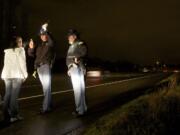 Washington State Patrol Cadet Aleksandr Ignatov, center, administers a field sobriety test to a DUI suspect on state Highway 14 while Trooper Bennie Taylor observes and takes notes.