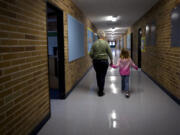 Staff assistant Sharleen Smith escorts a student to her first grade class at Ellsworth Elementary School in 2011.