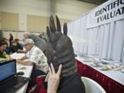 Expert appraiser Kathleen Victor tries on a wood carved mask on Saturday to get a better idea about what it was used for.