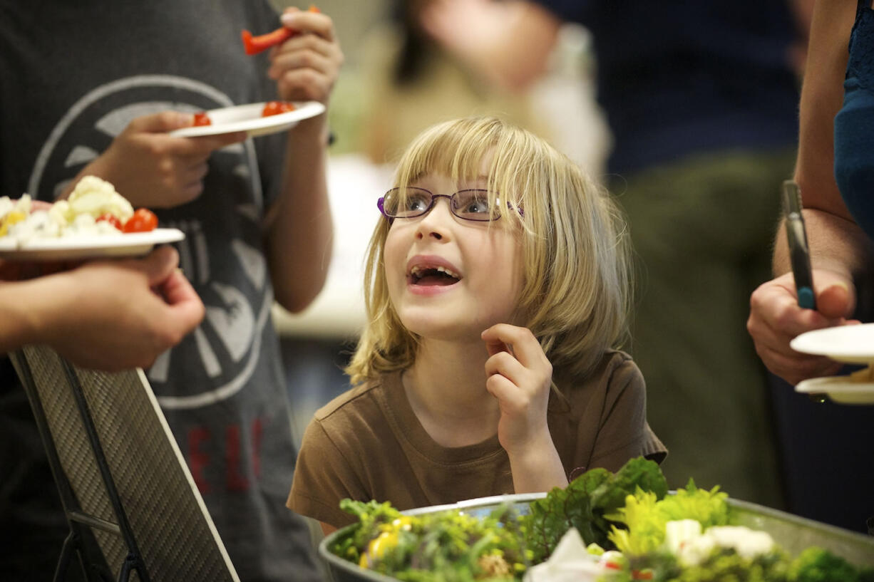 Cora Billingsley, 6, of Vancouver looks up from a bowl of vegetables as she waits to get a carrot Monday April 22, 2013 at the Grow Vancouver: Earth Day, Seed Swap and Spring Food Challenge at Clark College in Vancouver, Washington.