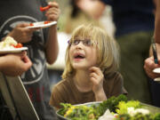 Cora Billingsley, 6, of Vancouver looks up from a bowl of vegetables as she waits to get a carrot Monday April 22, 2013 at the Grow Vancouver: Earth Day, Seed Swap and Spring Food Challenge at Clark College in Vancouver, Washington.