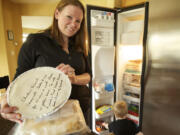 Julia Schetky shows off some of the meals she received at a moms group food swap last month, while her son, Ethan, checks out the other food in the freezer at the family home in Salmon Creek.