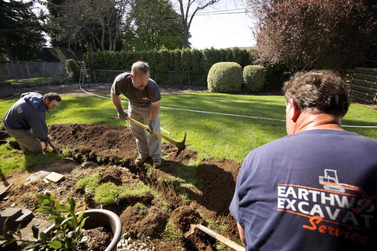 Earthworks Excavating Services employees, from left, Nathan Eterno, Jeff Eterno and Andrew Aasen, dig a power trench.