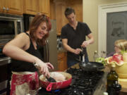 Paleo in a Pinch blogger Mary Helmes prepares a paleo chicken dinner, Coq Au Vin, for her family Tuesday as her husband, Aaron, and youngest daughter, Bella, keep her company in the kitchen.