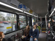 Poet Erin Iwata of Ridgefield, center in brown jacket, reads some moving poetry wtih Michael Atton of Vancouver aboard the no. 4 bus along Fourth Plain Boulevard on Dec. 14.