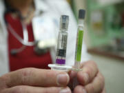 Lynnette Pickup, a nurse manager at Sea Mar Community Health Center, displays a new flu vaccine offered at the Vancouver clinic Friday. The quadrivalent vaccine protects against two strains of influenza A and two strains of influenza B.