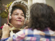 Heidi Pierson, left, holds still as Eileen Trestain, head of the costume department at the Fort Vancouver National Historic Site, checks out a bonnet Wednesday.