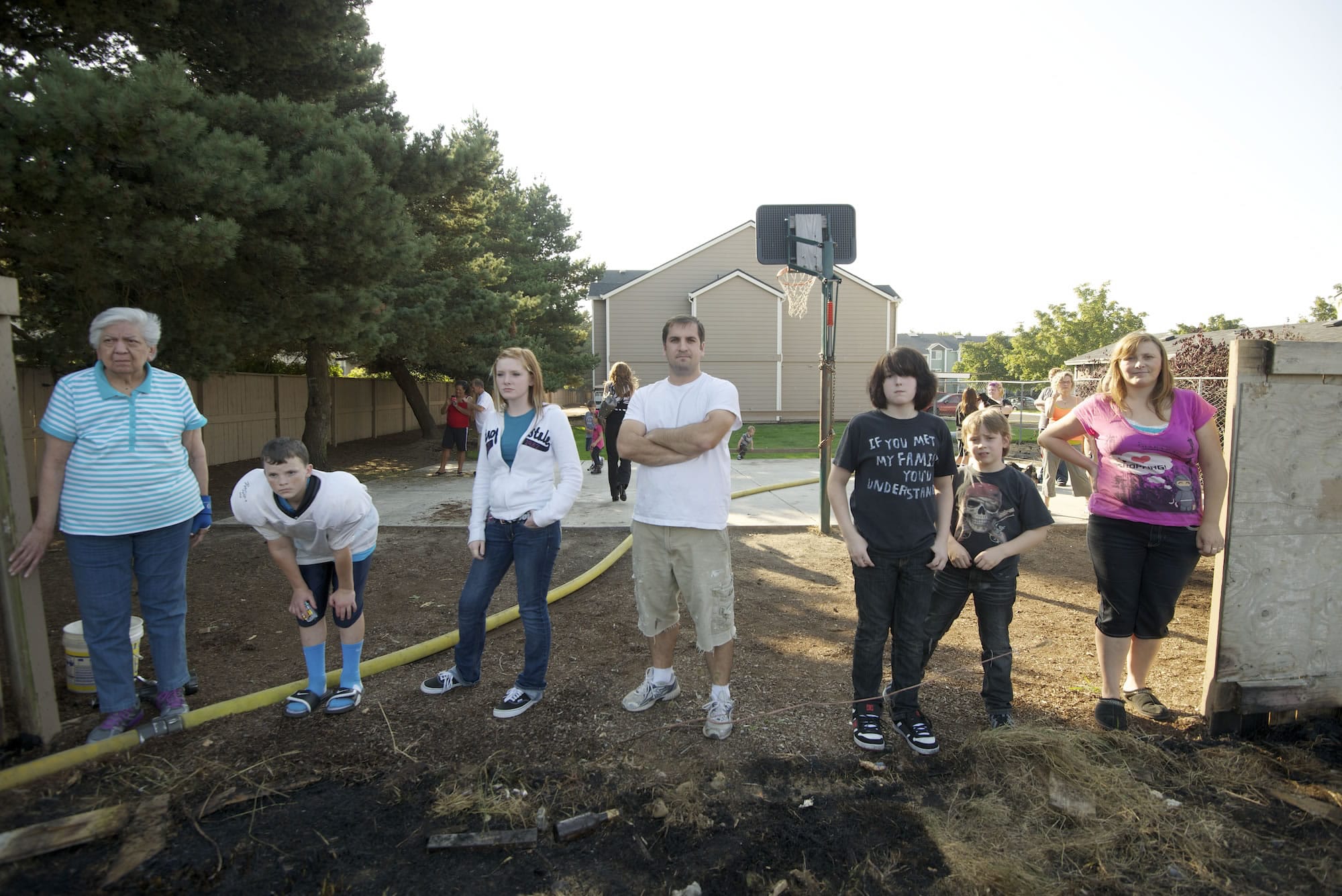 Residents of Prairie View Apartments watch from a broken-down fence as firefighters work to extinguish the blaze.