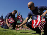 Ryan Beickel, left, an intern, and District 3 firefighter Andrew Wolf plant some of the 300 flags honoring the fatalities on Sept.