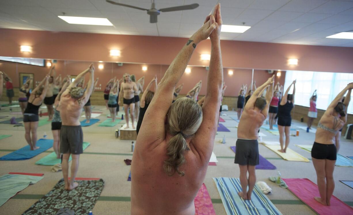 Instructor Elio Masa, back left, keeps up encouraging patter while students stretch out in 105 degree heat and 40 percent humidity at Bikram Hot Yoga Vancouver.