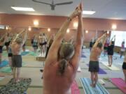 Instructor Elio Masa, back left, keeps up encouraging patter while students stretch out in 105 degree heat and 40 percent humidity at Bikram Hot Yoga Vancouver.