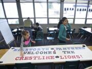 Ellsworth Elementary School fifth-graders Julia Papke, 11, left, and Jaspreet Sahota, 11, work in the library to make a sign welcoming 90 Crestline Elementary first-graders to their school. The banner will be hung at the school entrance to welcome the Crestline students on Thursday. &quot;I'm excited to share our school with kids who need our help,&quot; Jaspreet said.